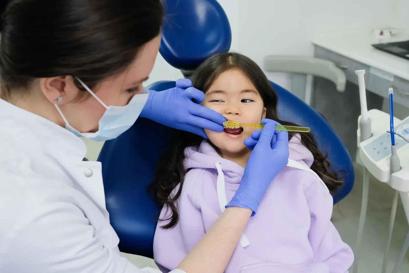 Dentist applying a protective dental sealant to the grooves of a child's back molars
