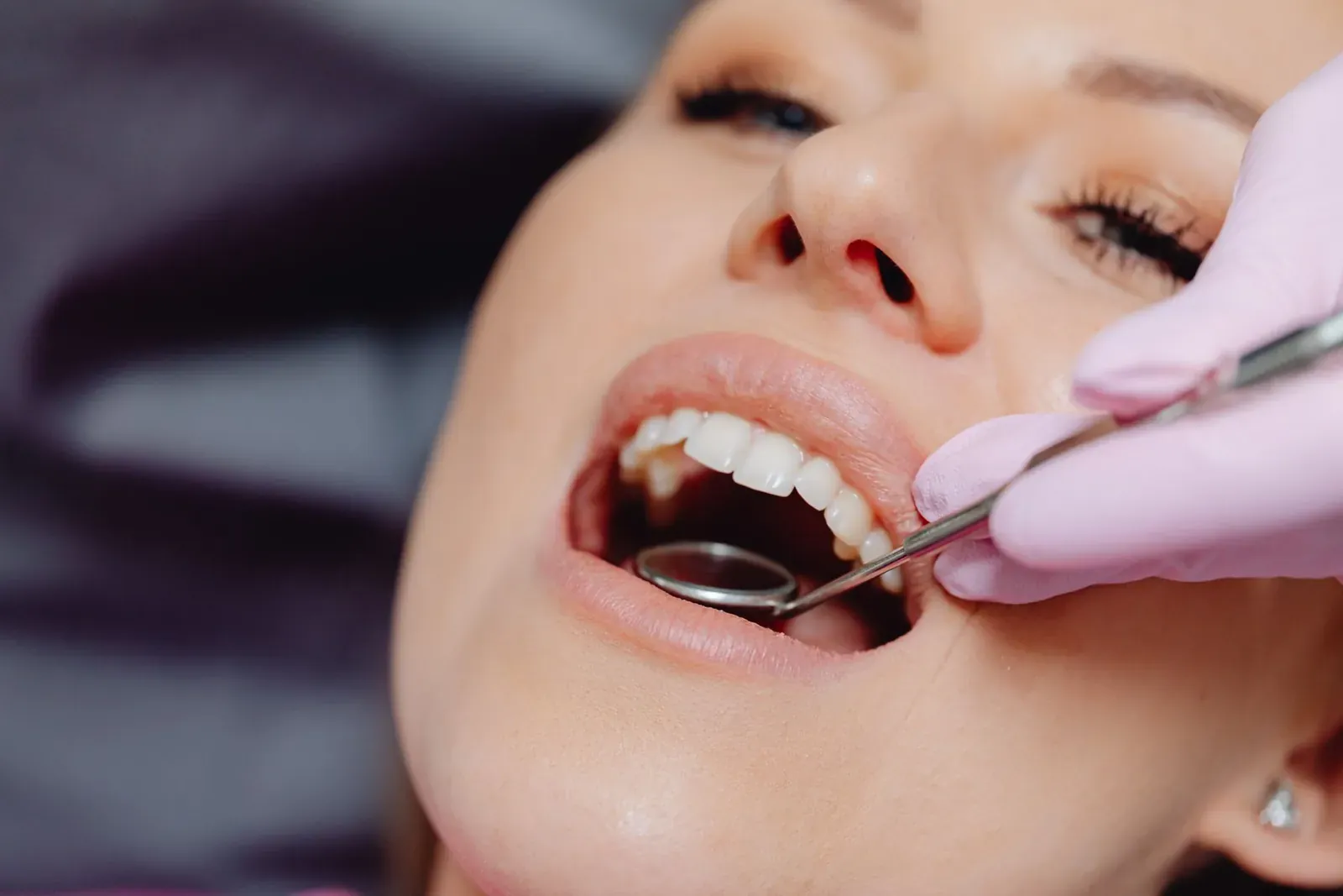Dentist checking a patient's gum line with a mouth mirror and periodontal probe for gum disease