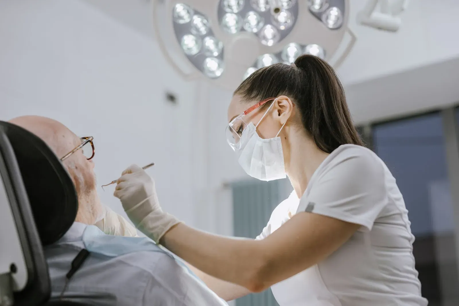 Dentist examining an older patient's teeth with a mouth mirror during a routine dental check-up