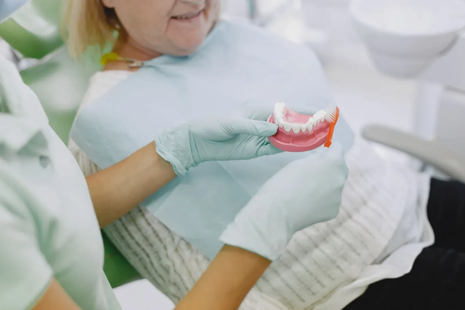 Dentist showing a full acrylic denture to a patient during a denture fitting