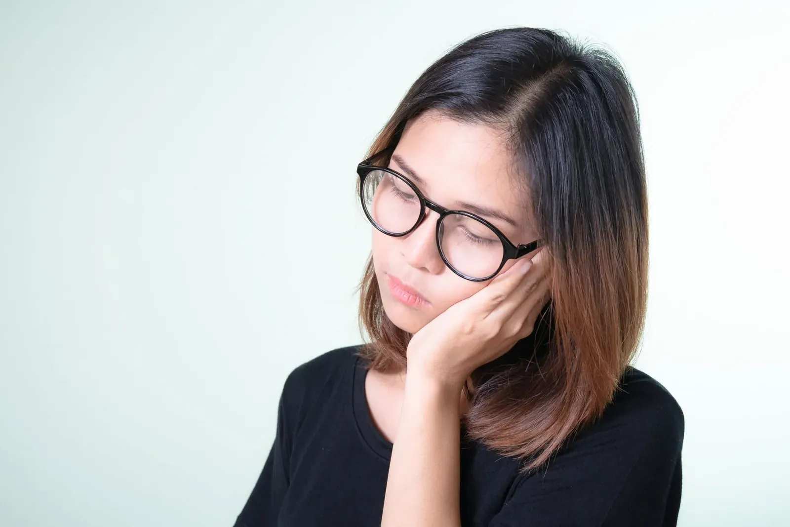 Woman wincing and holding her cheek from sharp tooth sensitivity to something cold
